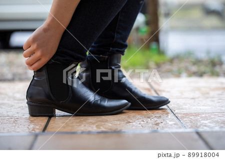 雨降りの庭でブーツを履く女性　Rain 89918004