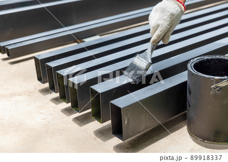 Worker painting steel post in construction site. Worker painting steel post in construction site. 89918337