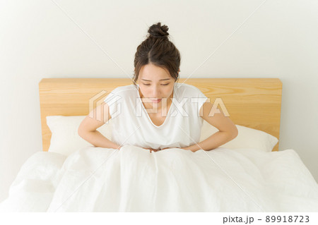 お腹を抑える女性　ベッド 89918723