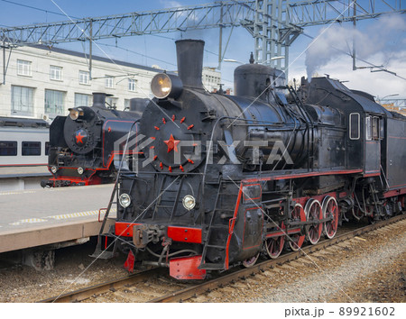 Old operating black steam locomotives with red stars at the passenger platforms 89921602