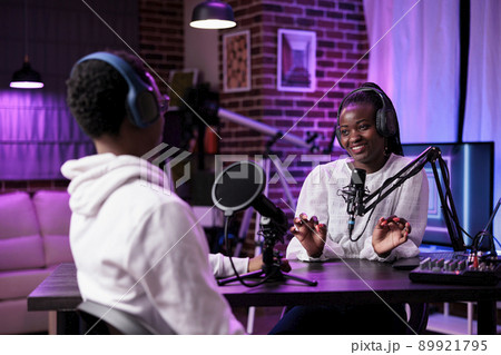 African american man and woman recording live podcast in studio, using sound production equipment. Happy influencers meeting to create social media content on internet broadcast. 89921795