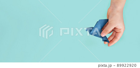 blue paper origami pigeon in children's hand on blue background blue paper origami pigeon in children's hand on blue background 89922920