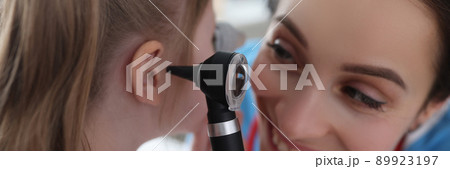 Ent woman examining ear of little girl with otoscope in clinic Ent woman examining ear of little girl with otoscope in clinic 89923197