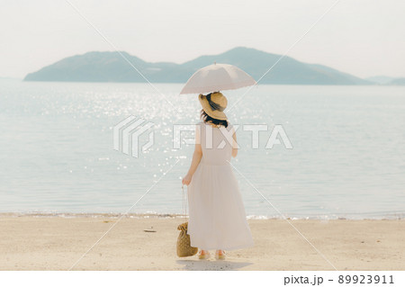ワンピース姿の日傘を持った女性と綺麗な夏の空 89923911