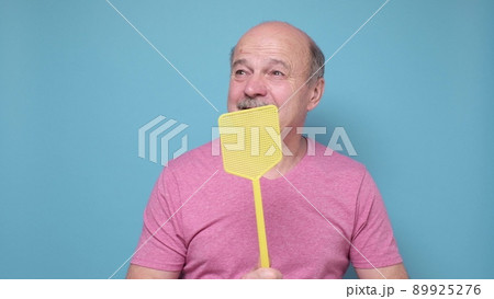 man with fly swatter trying to kill mosquito on blue background. man with fly swatter trying to kill mosquito on blue background. 89925276