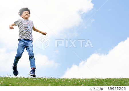 青空を背景に野原を駆ける小学生の男の子 青空を背景に野原を駆ける小学生の男の子 89925296