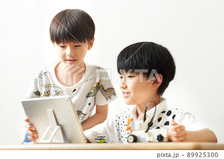 タブレットを見ながらプログラミング教材を組み立てる小学生 タブレットを見ながらプログラミング教材を組み立てる小学生 89925300