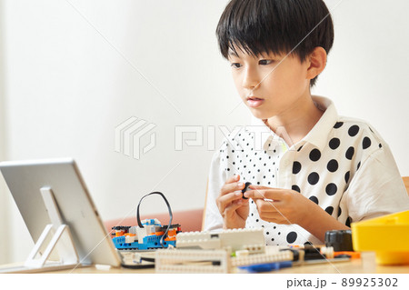 タブレットを見ながらプログラミング教材を組み立てる小学生 89925302