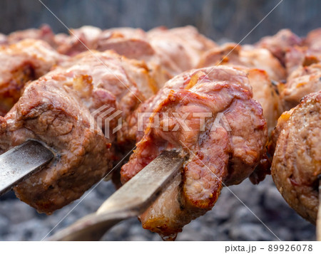 Juicy slices of pork meat are strung on skewers and grilled in charcoal grill. 89926078
