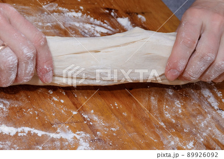 Female hands knead the dough on a wooden table. The process of preparing dough Female hands knead the dough on a wooden table. The process of preparing dough 89926092