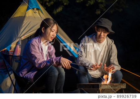 キャンプの夜にたき火をして談笑するカップル キャンプの夜にたき火をして談笑するカップル 89926739