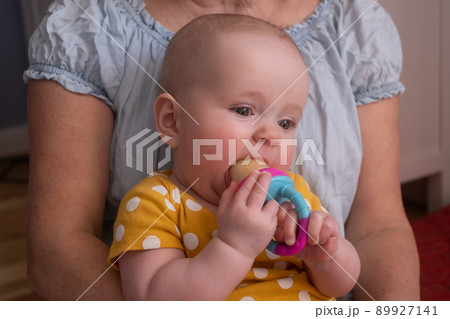 Seven month baby tasting apple with nibbler for firt time. 89927141