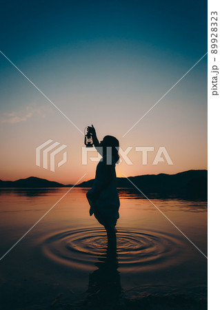 ワンピース姿の女性のシルエットと綺麗な夏の美しい夕焼け空の写真素材
