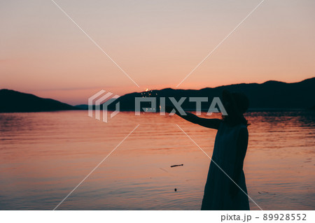 ワンピース姿の女性のシルエットと綺麗な夏の美しい夕焼けの写真素材