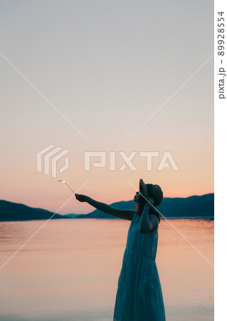 ワンピース姿の女性のシルエットと綺麗な夏の美しい夕焼け 89928554