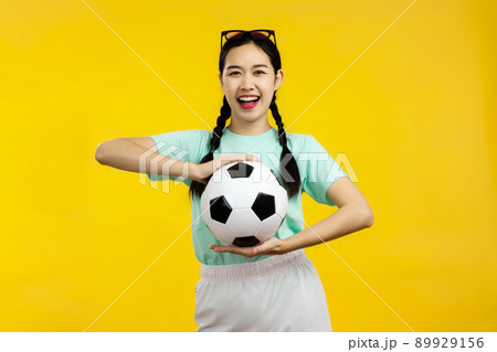 Portrait of Cheerful Asian woman holding a soccer ball isolated on yellow background, football sport concept 89929156