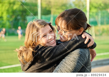 Portrait of happy mom and preteen daughter hugging together outdoor Portrait of happy mom and preteen daughter hugging together outdoor 89929434