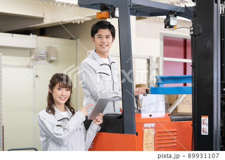 配送センターでフォークリフトを運転する男性と指示を出す若い女性作業員 89931107