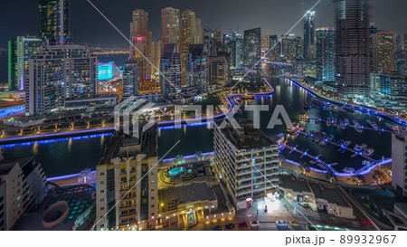 Dubai Marina with several boat and yachts parked in harbor and skyscrapers around canal aerial night timelapse. 89932967