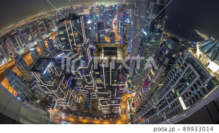 Skyline panorama of Dubai Marina showing canal surrounded by skyscrapers along shoreline all night timelapse. DUBAI, UAE 89933014