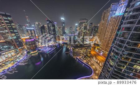 Aerial view to Dubai marina skyscrapers around canal with floating boats night timelapse Aerial view to Dubai marina skyscrapers around canal with floating boats night timelapse 89933476