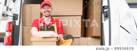 Man courier holding a parcel while sitting in the truck 89936639