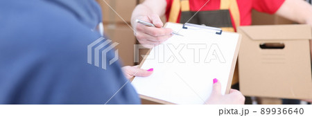 Courier holds parcel, woman signs document Courier holds parcel, woman signs document 89936640