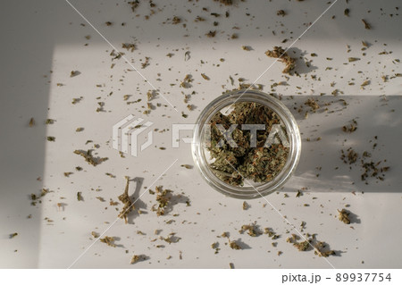 Weed Store. Glass jar with dried cannabis buds on white background with crushed weed. 89937754