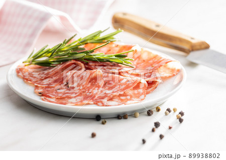 Sliced italian salami sausage with peppercorn on plate. Sliced italian salami sausage with peppercorn on plate. 89938802