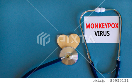 Monkeypox virus symbol. White card with concept words Monkeypox virus, wooden heart and stethoscope. Medical and Monkeypox virus concept. Copy space. 89939131