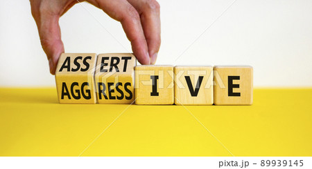 Aggressive or assertive symbol. Businessman turns wooden cubes, changes the word Aggressive to Assertive. Beautiful white background, copy space. Business, psychological aggressive assertive concept. 89939145