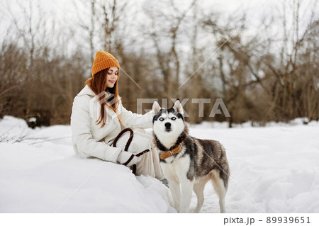 woman in the snow playing with a dog fun friendship winter holidays 89939651