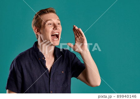 Close-up portrait of a ginger guy in navy t-shirt posing on blue background. Sincere emotions. Close-up portrait of a ginger guy in navy t-shirt posing on blue background. Sincere emotions. 89940146