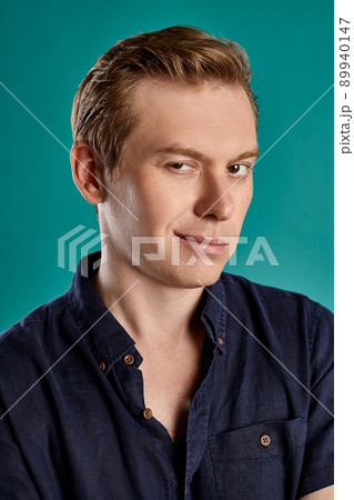 Close-up portrait of a ginger guy in navy t-shirt posing on blue background. Sincere emotions. Close-up portrait of a ginger guy in navy t-shirt posing on blue background. Sincere emotions. 89940147