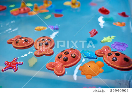 Multicolored plastic toy fish in pool for children's fishing, concept game. Multicolored plastic toy fish in pool for children's fishing, concept game. 89940905