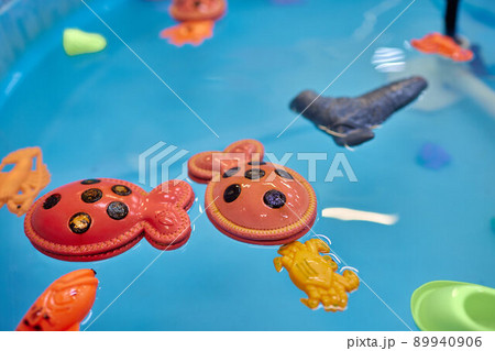 Multicolored plastic toy fish in pool for children's fishing, concept game. Multicolored plastic toy fish in pool for children's fishing, concept game. 89940906