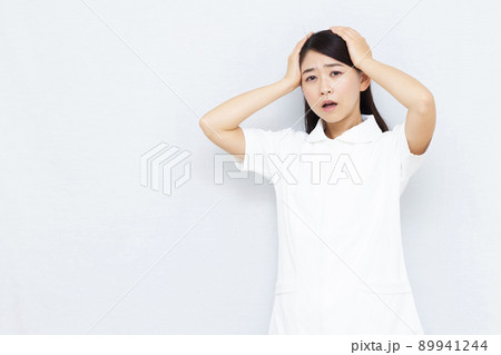 頭を抱えている30代の女性看護師 頭を抱えている30代の女性看護師 89941244