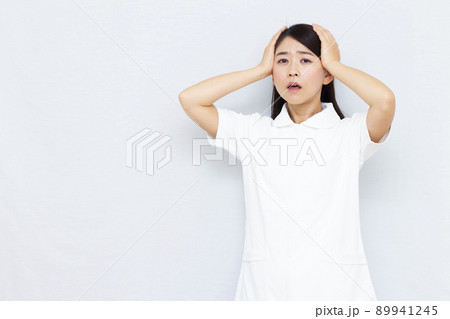 頭を抱えている30代の女性看護師 頭を抱えている30代の女性看護師 89941245