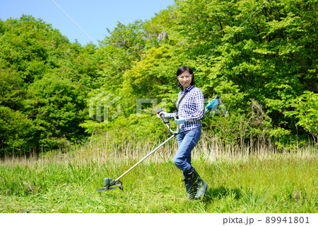 草刈り機で草刈りをする中年女性 89941801