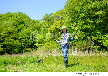草刈り機で草刈りをする中年女性 89941802