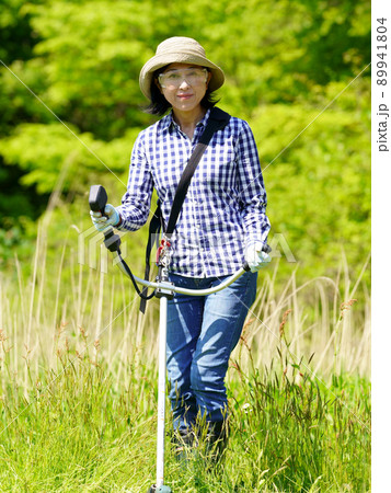 草刈り機で草刈りをする中年女性 草刈り機で草刈りをする中年女性 89941804