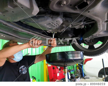 Car mechanic drain the old lubricant engine oil 89946059