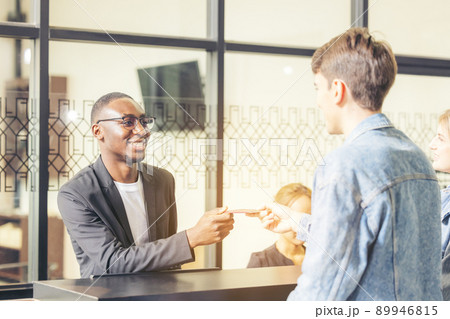 Guests handing their check-in information to the hotel receptionist with a smile Guests handing their check-in information to the hotel receptionist with a smile 89946815