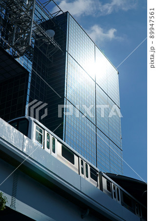 陽射しを受けながら都市風景の中をクールに走るゆりかもめ（7300系） 89947561