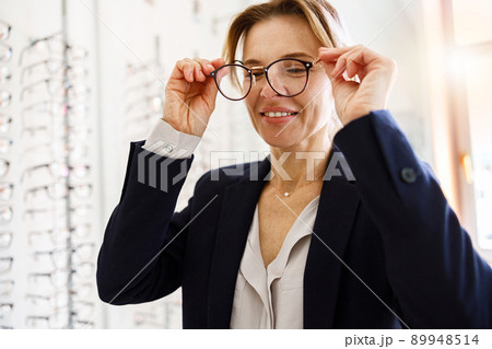 Woman client takes off the glasses that did not fit her in ophthalmic store 89948514