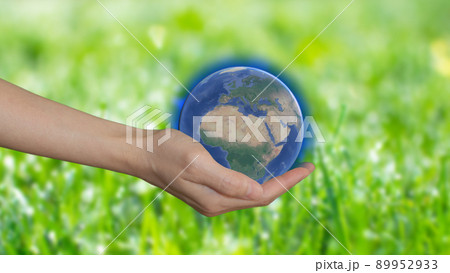 A woman's hand holding model of the planet on green background, earth day concept. Save the green world 89952933