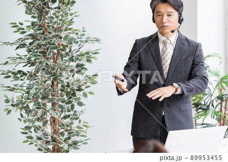 ヘッドセットをつけて人前で話をするビジネスパーソン 89953455