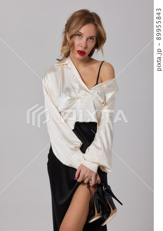 Beautiful stunning woman with red full lips, smokey eyes make up , shining perfect wavy hairs in elegant casual black dress posing on white background. 89955843