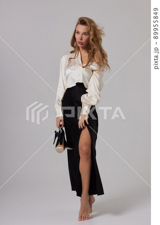 Beautiful stunning woman with red full lips, smokey eyes make up , shining perfect wavy hairs in elegant casual black dress posing on white background. 89955849