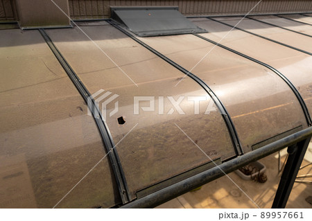 古くなり、汚れて穴の開いたカーポートの屋根 89957661